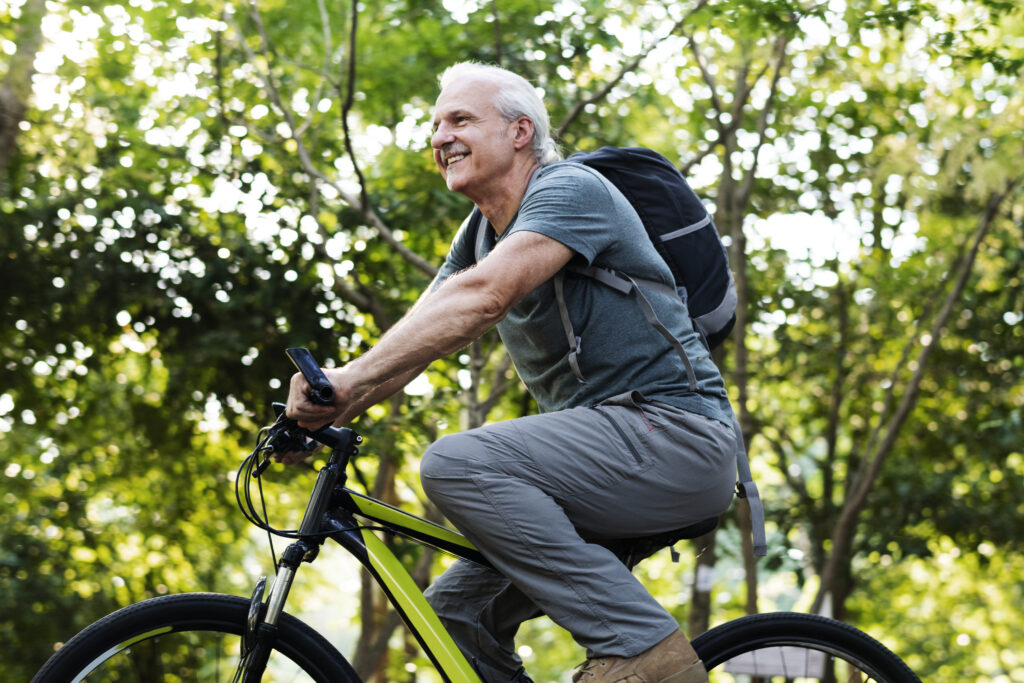 Senior man biking in the park as a form of eco transport